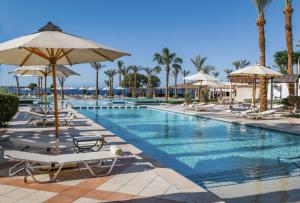 沙姆沙伊赫贾兹法纳拉度假酒店的度假村的游泳池,配有椅子和遮阳伞