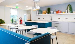 卡迪夫Staybridge Suites - Cardiff, an IHG Hotel的一间带桌子和蓝色沙发的餐厅