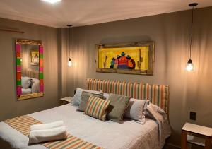 塔菲德尔瓦勒Hotel Colonial Tafi del Valle by DOT Tradition的卧室配有一张床,墙上挂有绘画作品