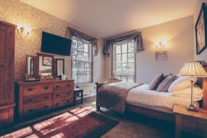 卡迪夫De Courceys Manor Suites & Cottages的一间卧室配有一张床、梳妆台和窗户。