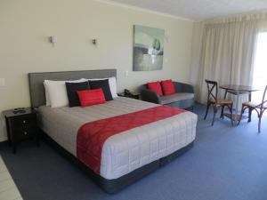 纳皮尔Harbour View Seaside Accommodation Napier的酒店客房带一张床、一张桌子和椅子