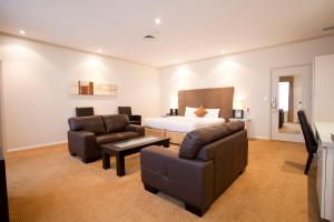 Doncaster East博梦德国际酒店的一间卧室配有一张床、一张沙发和椅子