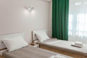 伊尔库茨克Апартаменты Изумруд возле Аэропорта на 2 гостя的绿帘间内的两张床