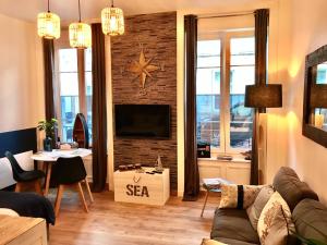 瑟堡Cherbourg Sea Sand的客厅配有沙发和砖墙电视