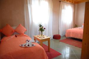 索维拉Riad Essaouira的一间卧室设有两张床,一张桌子上放着花瓶