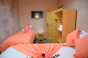 索维拉Riad Essaouira的一间卧室配有两张带橙色床单的床和电视。