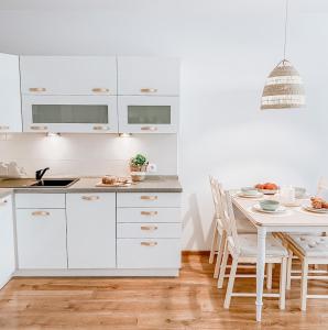 绿山城Apartamenty Flat White Ruczajowa的厨房配有白色橱柜和餐桌