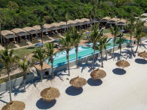 普拉伊拉多比莱尼San Martinho Hotel的享有带稻草遮阳伞的度假村游泳池的空中景致