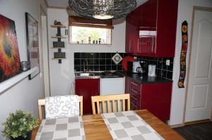 博里霍尔姆Södra Emmetorpsgatan 31的一间小厨房,厨房内配有红色橱柜和一张桌子及桌布