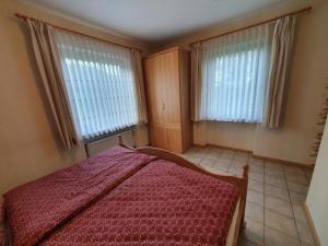 格罗尔斯泰因Eifel Ferienwohnung Dahmen的一间卧室设有红色的床和2个窗户。