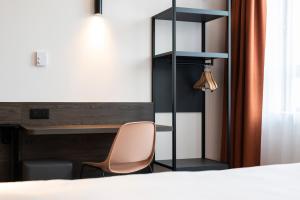 安特卫普B&B HOTEL Antwerpen Centrum的一间卧室配有一张桌子和一张椅子,位于床边