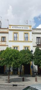 赫雷斯-德拉弗龙特拉Apartamentos El Alcazar de Jerez的黄色和白色的建筑,上面有标志