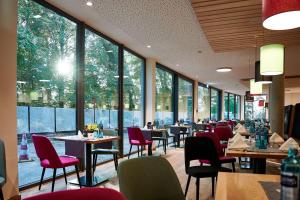 肯普滕Soloplan City Resort的餐厅设有桌椅和大窗户。