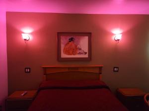 唐尼Deluxe Motel, Los Angeles Area的卧室配有一张床,墙上有两盏灯