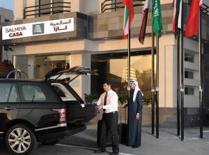 科威特莎米亚之家酒店的两个人站在一辆汽车旁边,车厢开