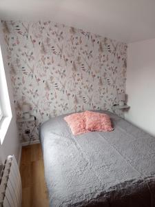 OffranvilleCHARMANTE MAISON PRES DE DIEPPE的一间卧室配有一张带花卉壁纸的床