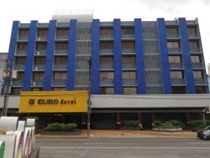 巴拿马城欧洲酒店的蓝色和黄色的建筑,前面有外科旅馆标志