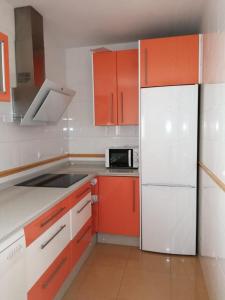 塞维利亚WISH SUITE MORERA的厨房配有橙色橱柜和白色冰箱