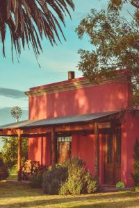 拉斯弗洛雷斯Casa de Campo La Colorada的前面有一棵树的红色房子