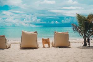 班塔延岛微风海滩小屋度假村的海滩上的3个枕头和1把椅子