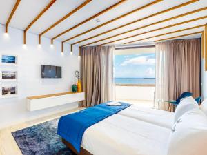 普拉亚达维多利亚Facing Bay Hostel的一间带大床的卧室,享有海景