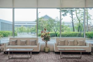 首尔LOTTE City Hotel Gimpo Airport的大型客房设有两张白色沙发,配有窗户