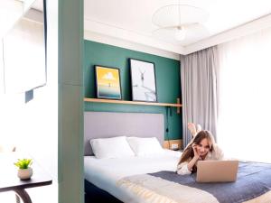 安锡阿纳西中心阿德吉奥公寓式酒店的一个小女孩躺在床上,手提电脑