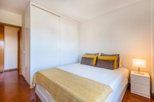 波尔图Foz Premium Retreat的卧室配有一张带黄色枕头的大型白色床。