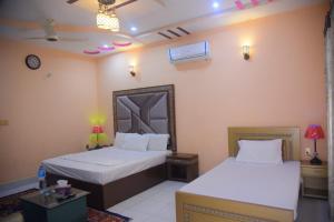 木尔坦Hotel Shaheen Continental Multan的一间卧室设有两张床和一张带台灯的桌子。
