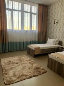 阿克套Tarlan Hotel的一间卧室设有两张床、一个窗户和一个地毯。