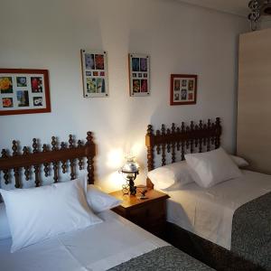 桑坦德Habitaciones en El Sardinero-Santander的一间卧室配有两张床和一张带台灯的桌子