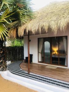卡尔皮蒂耶The Blue Lagoon Resort Kalpitiya的茅草屋顶房屋 - 带木甲板