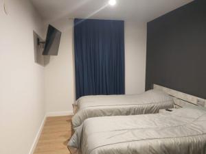 马里亚诺Apartamentos Hi Apartaments Santander 3000的一间设有两张床和蓝色窗帘的房间