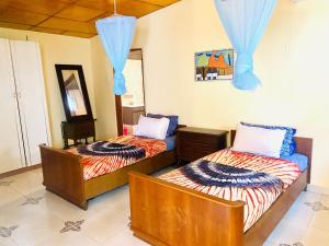 SanyangJungle Beach Resort的配有蓝色窗帘的客房内的两张床