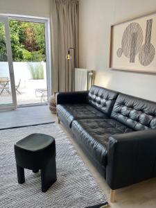 根特Unique luxury apartment with cosy garden!的客厅配有黑色真皮沙发和凳子