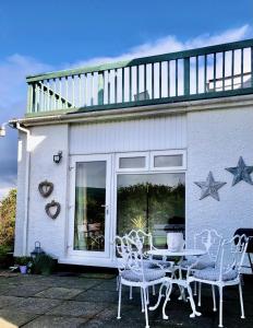 BallygalleyBallygally Seaview and Garden Hideaway的房屋前设有带桌椅的天井。