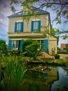 CrainLes rêves d'Angèle的一座带蓝色百叶窗的房子,前面有一个池塘
