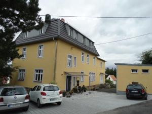 霍恩斯泰因Ferienwohnung Sonnenblick的一座黄色的房子,前面有汽车停放
