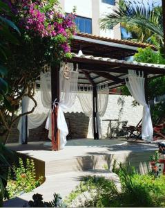 巴拉多库努Pousada Mirante do Cunhaú的花园内带白色窗帘的木制凉棚