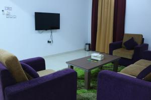 尼兹瓦奥卡拉姆酒店的一间设有椅子和桌子的等候室以及一台电视
