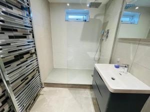 凯尼尔沃思NEW MODERN STUDIO APARTMENT, PARKING, Netflix的白色的浴室设有水槽和淋浴。