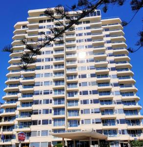 黄金海岸南十字海滨度假公寓 的一座高大的白色公寓楼,配有遮阳伞