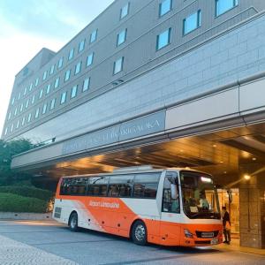 东京Hotel Cadenza Tokyo的停在大楼前的橙色和白色的公共汽车