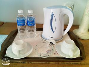 诗巫Kawan Hotel的包括茶壶、杯子和水瓶的托盘