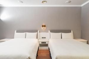 宜兰市宜兰富翔大饭店的配有白色床单的酒店客房内的两张床