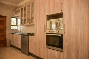哈博罗内Apartment Two-One-Two Eleven的厨房配有木制橱柜、烤箱和水槽。