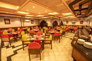 拜拉哈瓦Hotel Nirvana by Luxury International的餐厅设有桌椅和红色及黄色的椅子
