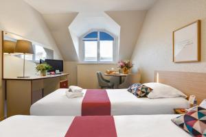 南特Appart'City Classic Nantes Viarme的酒店客房设有两张床和一张桌子。