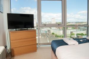 格拉斯哥City Views Apartment City Centre FreeParking的卧室,窗户前的梳妆台上配有电视