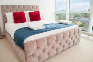 格拉斯哥City Views Apartment City Centre FreeParking的一张带红色枕头的大床和大窗户